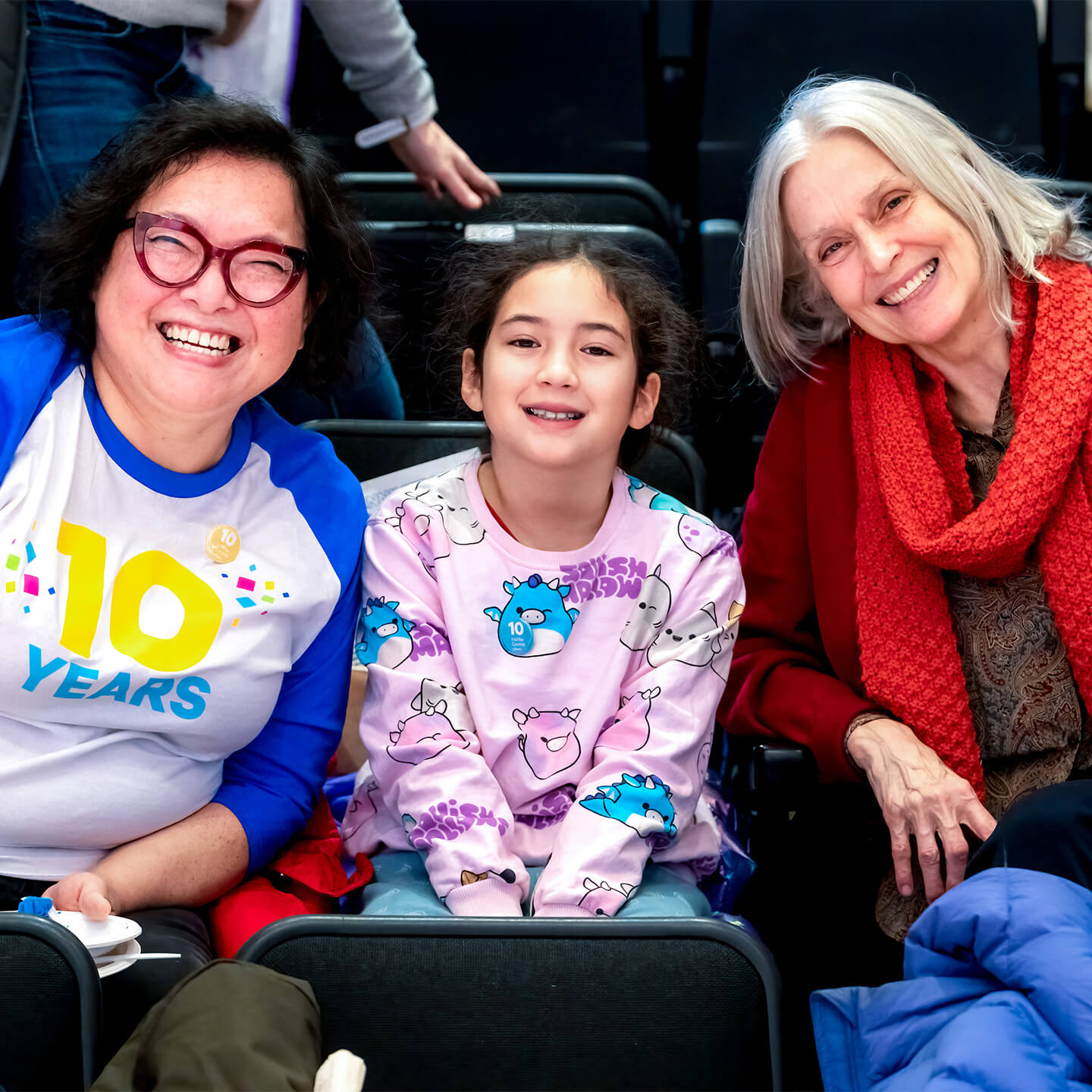 3 people posing for a photo sitting at the Paul O’Regan Hall during the anniversary celebration.